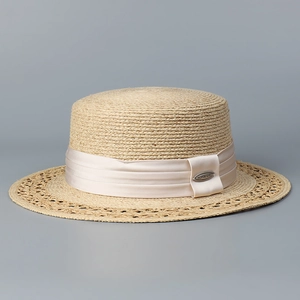 Detail of a boater hat featuring wide hollow-out woven brim and champagne silk ribbon