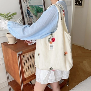 Detail of floral embroidery on cream canvas tote bag showing high-quality stitching