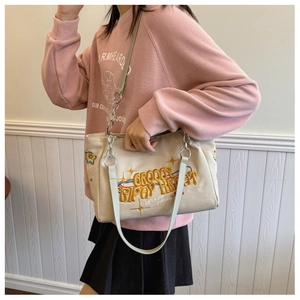 Canvas tote bag with colorful star embroidery and letter print shown on model shoulder