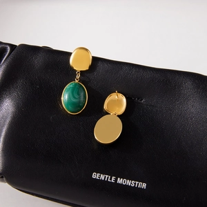 Luxurious gold stainless steel earrings with green resin pendants on leather background