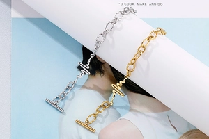 Close-up of gold and silver heartbeat pulse bracelets featuring an elegant OT toggle clasp