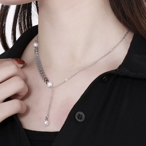 Detailed view of silver wheat ear necklace with pearls worn on a woman's collarbone
