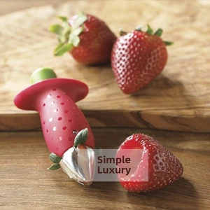Practical stainless steel strawberry huller tool removing the stem on a wooden tray