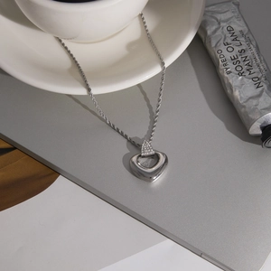 Detailed view of silver heart pendant necklace with twist chain and rhinestone detail