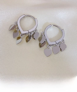 Macro detail of silver heart hoop earrings with four small heart charms on silk cloth