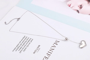 Detailed view of silver heart pendant necklace on a magazine background with lobster clasp