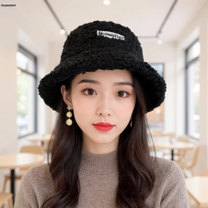 Close-up of black fleece bucket hat with white logo patch and warm texture