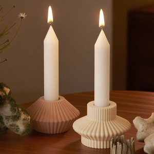 Close-up of ribbed resin candle holders in pink and cream with lit taper candles