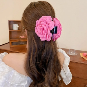 Rear view of a model wearing a pink fabric flower hair claw clip for a French updo style