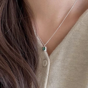Close-up of 925 sterling silver necklace featuring an oval green gemstone pendant