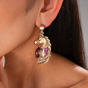 Close-up of vintage gold horse head earrings with red rubies and sparkling diamonds