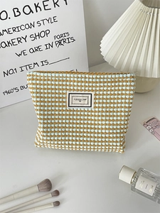 Detail of blue and yellow popcorn knit makeup bag with PLEASANT TIME woven label