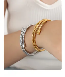 Detail of layered gold and silver snake bone bracelets with textured industrial design