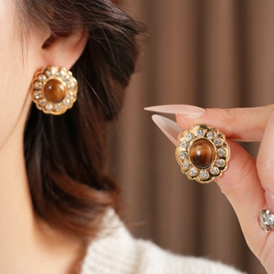 Dettaglio di orecchini vintage a fiore con occhio di tigre e strass scintillanti