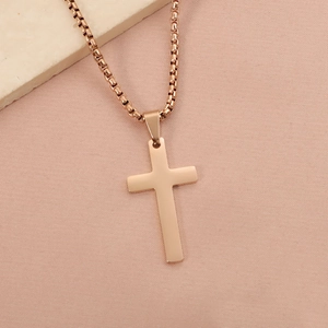 Detail of rose gold cross pendant necklace on pearl chain against stone background