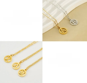 Vue macro détaillée des pendentifs alphabet ronds évidés en acier titane poli