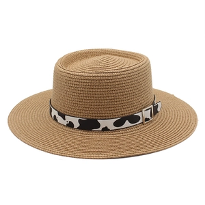 Close-up of a straw sun hat with a cow print band and silver metal buckle detail