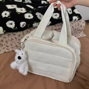 White quilted puffer toiletry bag detail with zipper closure and cute plush dog charm