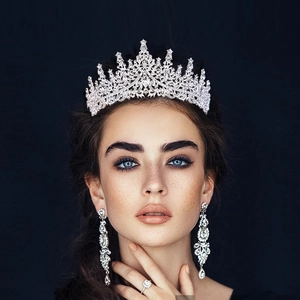 Detail view of luxury bridal tiara set with crystal drop earrings on a dark background