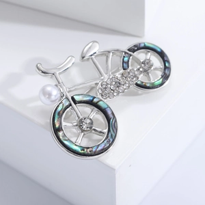 Close-up of silver bicycle brooch with iridescent abalone shell inlay and rhinestones