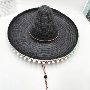 Detalle de sombrero mexicano de paja negro con pompones blancos y barboquejo