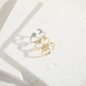 Detailed view of sun and moon adjustable open rings on a white textured stone background