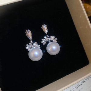 Vue macro de boucles d'oreilles en argent avec perles blanches et grappes de zircones