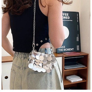 Fashionable silver sequin crossbody bag with metallic chain strap worn by a model
