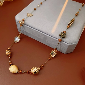 Dettaglio macro della collana boho con perle d'ambra e ciondoli a farfalla in bronzo antico