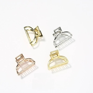 Detail of four metallic geometric hair claws in gold, silver, and rose gold finishes