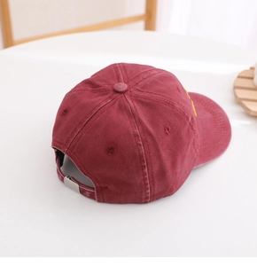 Close-up of washed burgundy baseball cap with metallic buckle and embroidery details