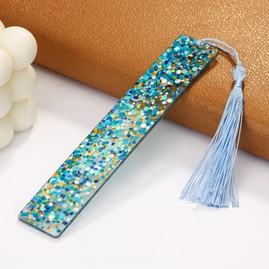 Detailed view of rectangle resin bookmark with teal sequins and matching light blue tassel