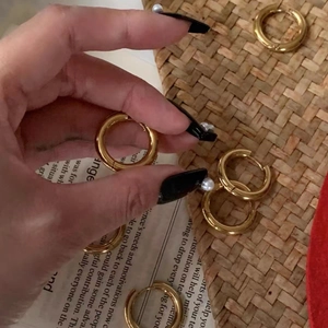 Fashionable gold double-layer stainless steel hoop earrings held by hand on stylish background