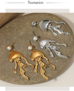 Detailed view of silver and gold jellyfish earrings with pearls on a natural stone