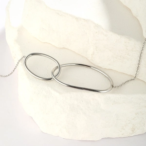 Minimalist silver stainless steel double circle bracelet on a white stone pedestal