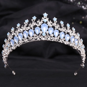 Detailed view of silver Baroque tiara with blue crystals on black textured fabric