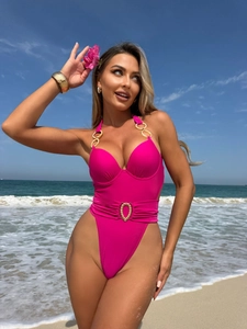 Detail view of pink one-piece swimsuit featuring gold ring accents and decorative waist buckle