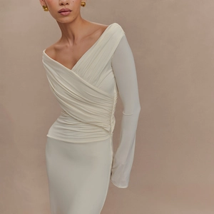 Détail d'une élégante robe beige à manches longues et épaules dénudées, tissu drapé