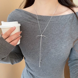 Élégant collier avec pendentif nœud argenté et pompons porté par un mannequin