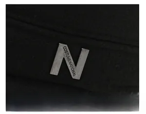 Detailed close-up of metallic N emblem and brand engraving on black wool hat