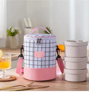 Detail view of pink checkered cylindrical lunch bag with three stackable boxes and strap