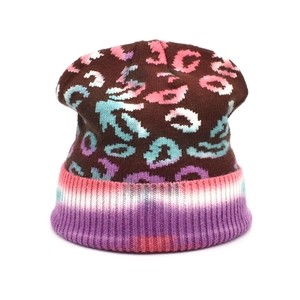 Detailed close-up of leopard pattern knit beanie with pink ribbed cuff and vibrant tie-dye colors
