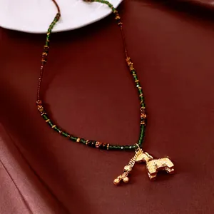 Handcrafted beaded necklace featuring green faceted beads and a golden horse pendant