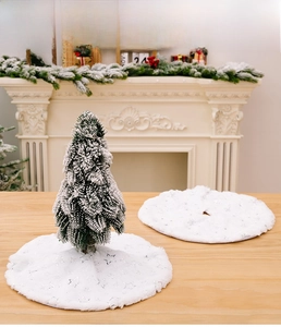 Close-up of white plush Christmas tree skirt with silver sequin stars on a wooden table