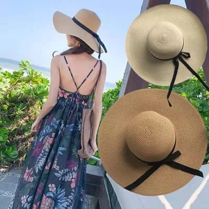 Detail of straw sun hats in khaki and beige featuring elegant black ribbon bow accents