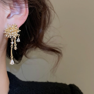 Close-up of gold fireworks tassel earrings with pearls and zircon on model's ear