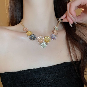 Detail of colorful enamel daisy necklace with floral petals and gold chain on model