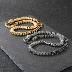 Detailed scale texture of gold and silver snake necklaces on dark rock surface