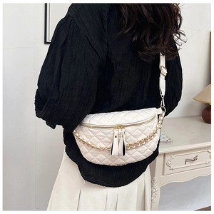 Detail of quilted diamond pattern and gold chain strap on cream white crossbody bag