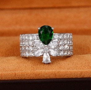 Macro detail of luxury wide band ring with pear-cut emerald zircon and micro-paved diamonds